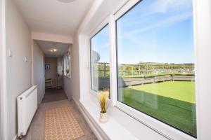 d'un balcon avec une grande fenêtre donnant sur un court de tennis. dans l'établissement Laudervale East Penthouse Loch Lomond, à Balloch
