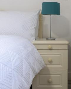 a bed with a white comforter and a lamp on a night stand at Oak Lodge in Welling