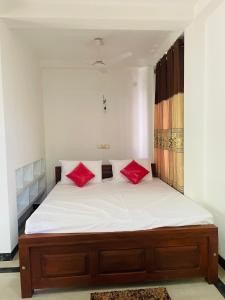 a bedroom with a bed with red pillows on it at Villa bella vista ahangama in Ahangama