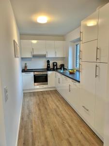 eine Küche mit weißen Schränken und einem Holzboden in der Unterkunft 1904 - Am Kurpark in Dahme