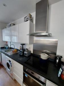 a kitchen with white cabinets and a black counter top at London Luxe Rooms in Surbiton