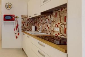 a kitchen with a sink and a tile wall at LucevanLeStelle - Full Comfort Quiet Apartment by the Promenade in Viareggio