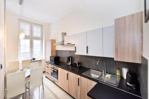 cocina con armarios blancos y encimera negra en Gdańskie Apartamenty - Apartamenty na Świetego Ducha z 2 sypialniami, en Gdansk