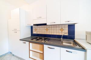 a kitchen with white cabinets and a sink at Vapelo a Marina di Campo in Marina di Campo