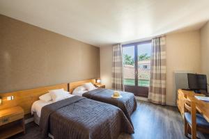 a hotel room with two beds and a television at Hôtel Les Grenettes in Sainte-Marie-de-Ré