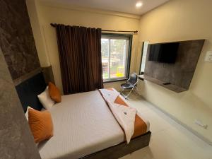a bedroom with a bed and a tv and a window at Hotel Grand Bella in Mumbai