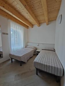 two beds in a room with a wooden ceiling at casa antico borgo - appartamento 1 in Assenza di Brenzone
