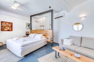 1 dormitorio con cama blanca y sofá en Skiff - Transformed studio on the water's edge, en La Canea