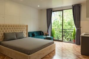 a bedroom with a large bed and a balcony at LÉ BOISE HOTEL Đà Lạt in Da Lat