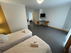 a hotel room with two beds and a table and chairs at Hôtel La Pierre Bleue in Saint-Gildas-de-Rhuys