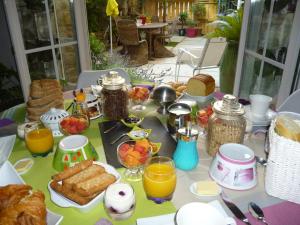 uma mesa com comida para o pequeno almoço e sumo de laranja em Chambres d'Hôtes La Rose des Vents em Ginestas