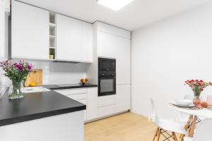 a kitchen with white cabinets and a black counter top at Promienistych 2 in Kraków