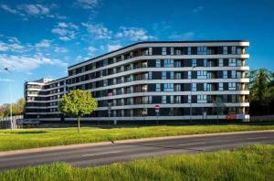 a large building with a tree in front of a street at Promienistych 2 in Kraków