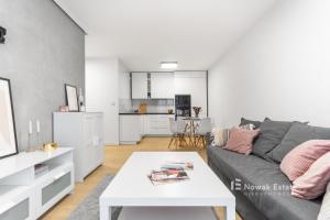 a living room with a gray couch and a white table at Promienistych 2 in Kraków