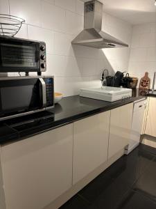 a kitchen with a microwave and a sink at Souterrain aan zee in Noordwijk