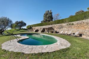 a swimming pool with a stone wall and chairs around it at Les Corts De Biosca in Castelltallat