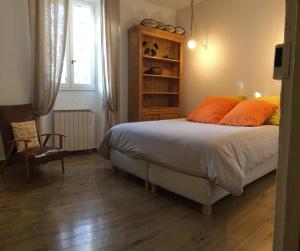 a bedroom with a bed with orange pillows and a chair at Provencal farmhouse, pool, pool house, countryside Plan d’Orgon, Provence - 8 people in Cavaillon +30 photos