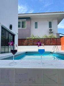 Dos copas de vino sentadas en una mesa junto a una piscina. en Psalms 23 Residence, en Bangkok