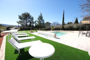 a pool with white benches and a table and a table and chairs at very beautiful villa with private pool in the luberon enjoying a magnificent view of the durance valley, located in puget – 10 people. in Puget