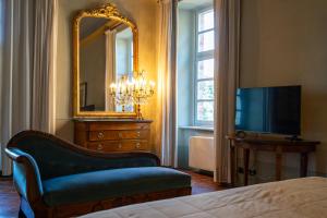 a bedroom with a mirror and a chair and a tv at Foresteria del Castello di San Giorgio Canavese in San Giorgio Canavese