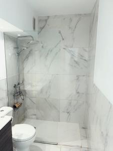 a white bathroom with a shower and a toilet at Sunny Oceanview studio apartment Ponderosa in Costa Adeje in Playa de las Americas