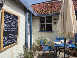 a table and chairs outside of a restaurant with an umbrella at The Sun in Wells