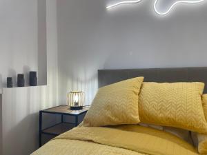 uma cama com um edredão amarelo e uma mesa lateral em Silesia Blue2 Apartment - Katowice em Katowice