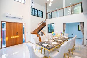 a dining room with a long table and white chairs at Psalms 23 Residence in Bangkok