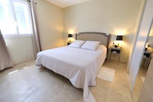 a bedroom with a white bed with two pillows at charming house with private pool in the heart of the village of aureille in the alpilles, 6 people. in Aureille +27 photos