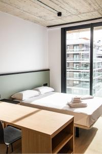 two beds in a room with a table and a window at Atenea Living in Mataró