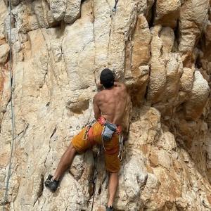 un homme grimpe sur un mur de roche dans l'établissement Villa Corallina Relais & Climbing Center, à San Vito Lo Capo