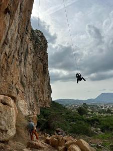 une personne sur une corde suspendue à une falaise rocheuse dans l'établissement Villa Corallina Relais & Climbing Center, à San Vito Lo Capo