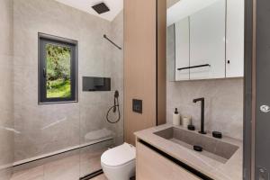 a bathroom with a sink and a toilet and a shower at Villa Optima by Villa Plus in Peroúlion +18 photos