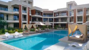 an apartment complex with a swimming pool with chairs and umbrellas at Maharani Apartments in Diani Beach