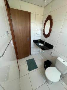 ein Badezimmer mit Toilette, Waschbecken und Spiegel in der Unterkunft Chale Ville Maramar 401 in Luis Correia