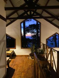 a living room with large windows and a wooden floor at Villa Kinyonga, Camp Mawingu in Muheza