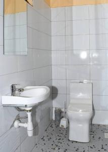a white bathroom with a sink and a toilet at Airport Bliss House in Kisumu
