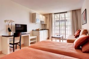 a bedroom with a bed and a desk and a kitchen at Grupotel Club Menorca in Son Xoriguer
