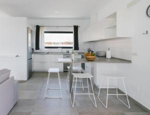 una cocina con armarios blancos y taburetes blancos en Casa Agua Nueva 53, en La Frontera