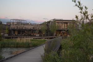 a building with a wooden walkway next to a river at Basecamp Amsterdam in Amsterdam