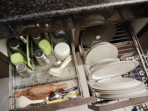 a metal dish rack with dishes and utensils under a sink at Green Bacchus stays Self Check-In in Gurgaon