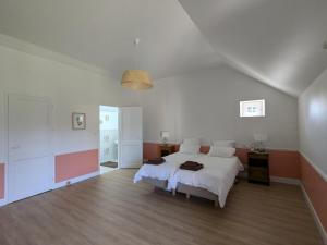a bedroom with a white bed and a wooden floor at La Maison Cornon in Trumilly