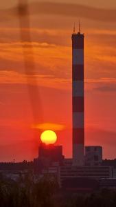een zonsondergang met een vuurtoren op de achtergrond van een stad bij Apartament WARSZAWSKA in Kielce