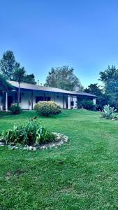 a building with a green field in front of it at Bayas Coloradas, San Lorenzo, Salta in San Lorenzo