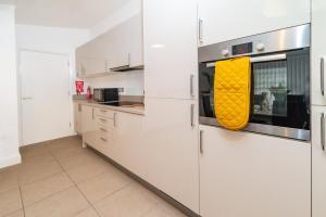 ハンティンドンにあるStylish 2 Bedroom Apartment By Your Lettings Short Lets & Serviced Accommodation Peterborough With Free WiFi,Parking And Moreのキッチン(白いキャビネット、黄色のオーブン付)