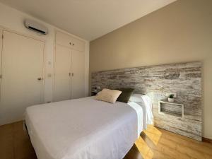 ein Schlafzimmer mit einem weißen Bett und einer Holzwand in der Unterkunft Agi Sant Jordi in Roses