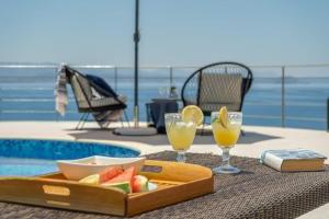 taca z owocami i napojami na stole przy basenie w obiekcie Villa Hemera ocean view private heated pool w mieście Chorafakia