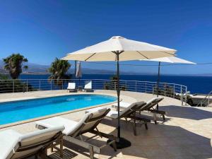 basen z krzesłami i parasolem nad oceanem w obiekcie Villa Hemera ocean view private heated pool w mieście Chorafakia