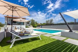 une cour avec une piscine et un mobilier de jardin avec un parasol dans l'établissement Villa Ampelaki - Premium Villa with heated pool, à Kounoupidhianá