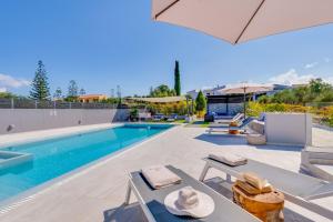 une piscine avec des chaises et des parasols à côté d'une piscine dans l'établissement Villa Ampelaki - Premium Villa with heated pool, à Kounoupidhianá 72 autres photos